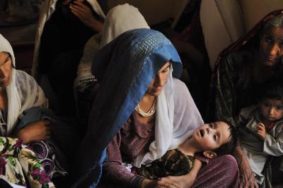 An Afghan woman holds her sick daughter