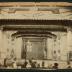 Photograph: View of stage in a music hall or theater, showing Trick House set and performers