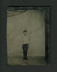 Photograph: Tintype portrait of a young boy with flag in background, circa 1870 