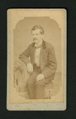 Photograph: Portrait of man seated on upholstered chair