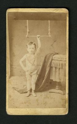 Photograph: Portrait of very young boy holding onto a trapeze