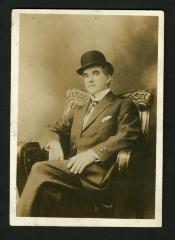 Photograph: Man in carved armchair wearing bowler hat