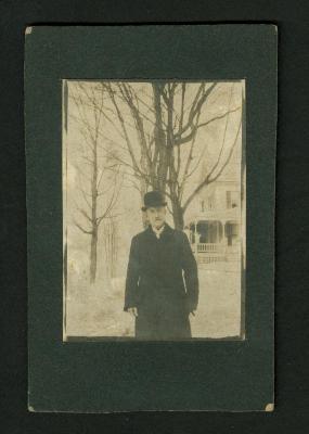 Photograph: Man standing with bare trees and house in background