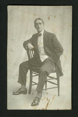 Postcard: Eddie F. Smith seated backwards on a chair
