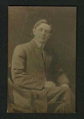 Photograph: Unidentified young man wearing medium colored suit sitting in armchair